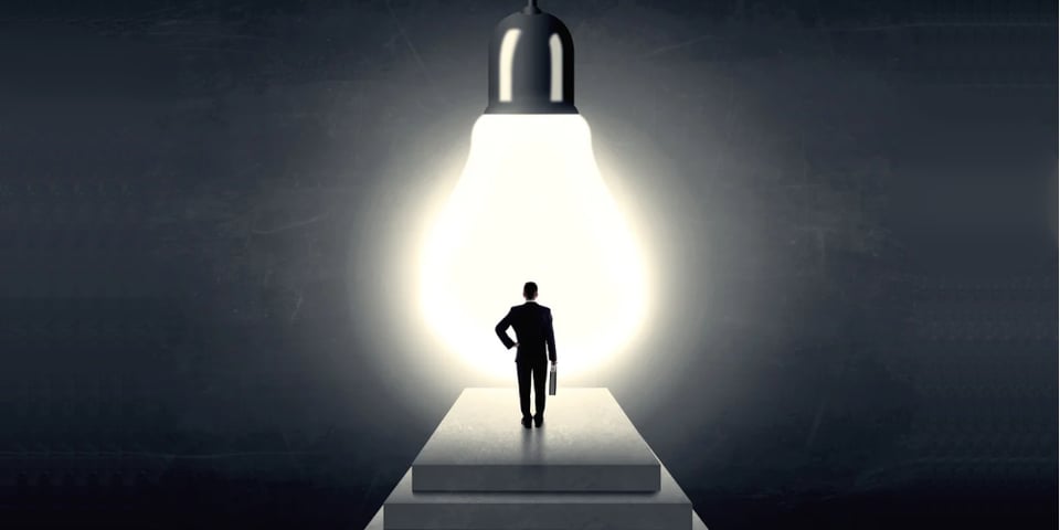 Businessman standing on a step in front of a huge light bulb, concept of having an idea